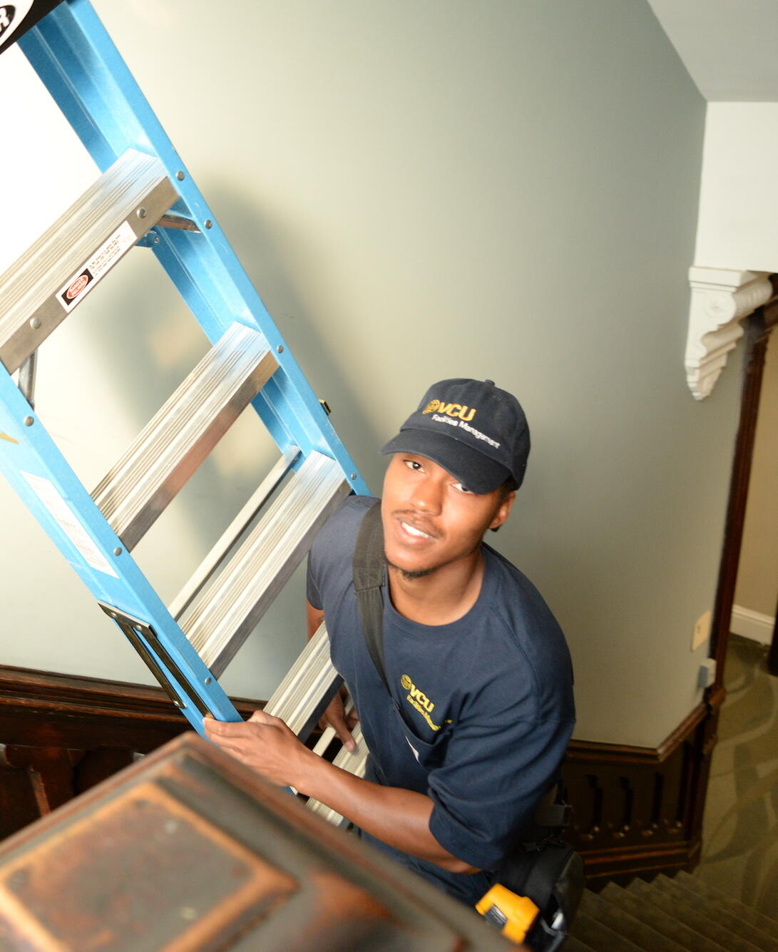 Jonathan Jones carrying a ladder up a flight of stairs
