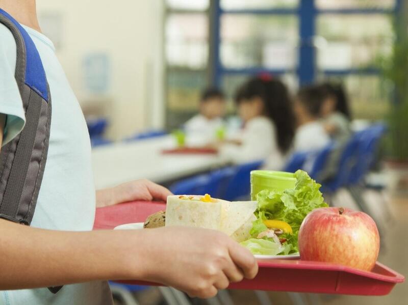 An elementary school student holding a lunch tray