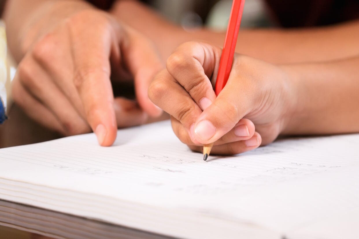 close-up of hands writing on a piece of paper