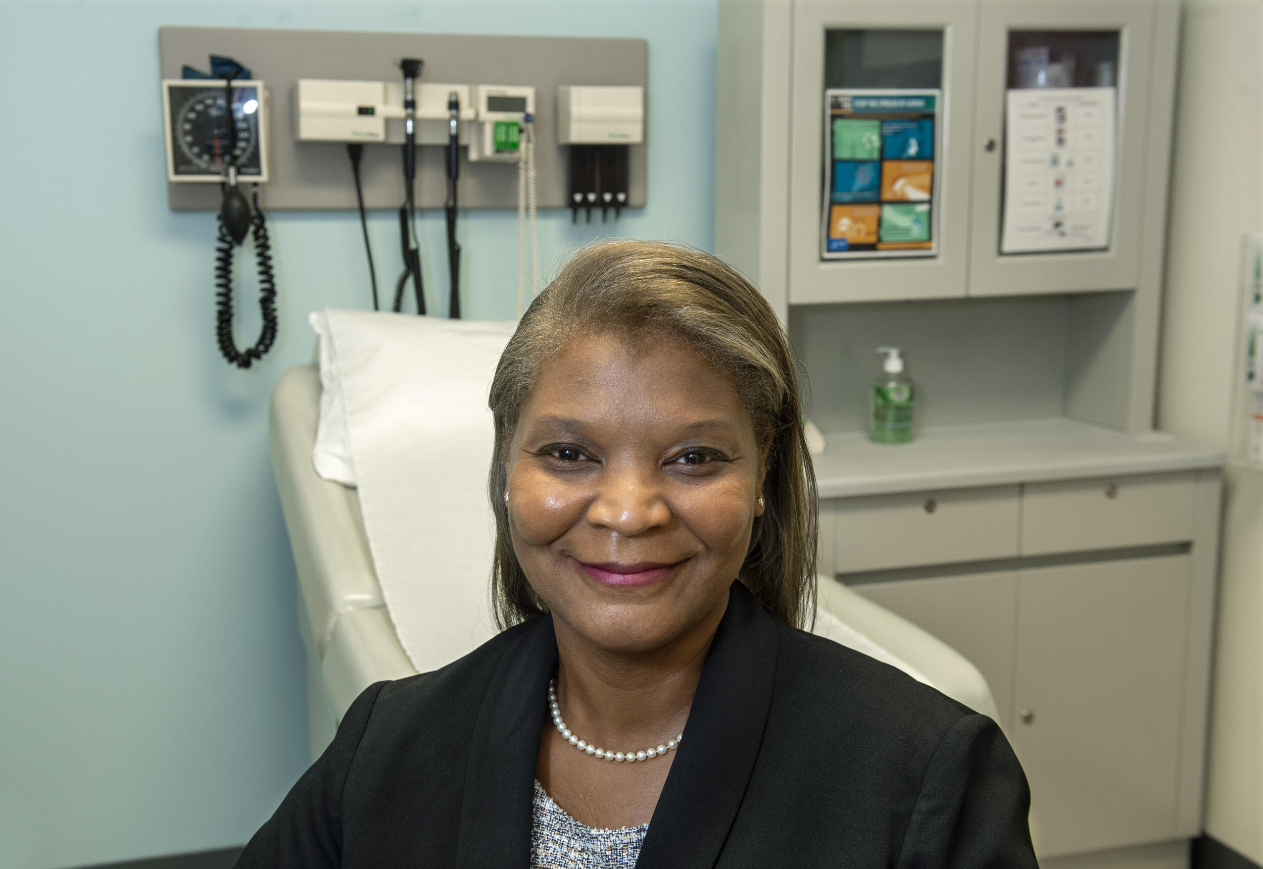 A woman wearing a sport coat smiling in an exam room 