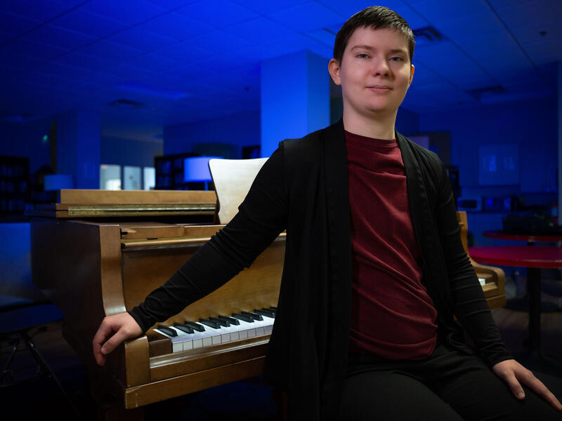 A photo of a man standing in front of a piano. 