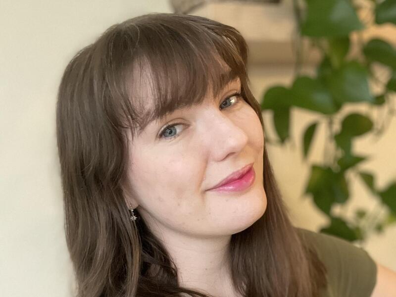 A woman with brown hair and an olive green shirt 