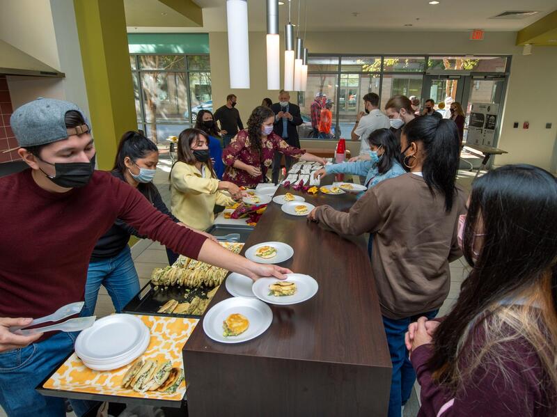 Students serving dishes of food to a line of other students.