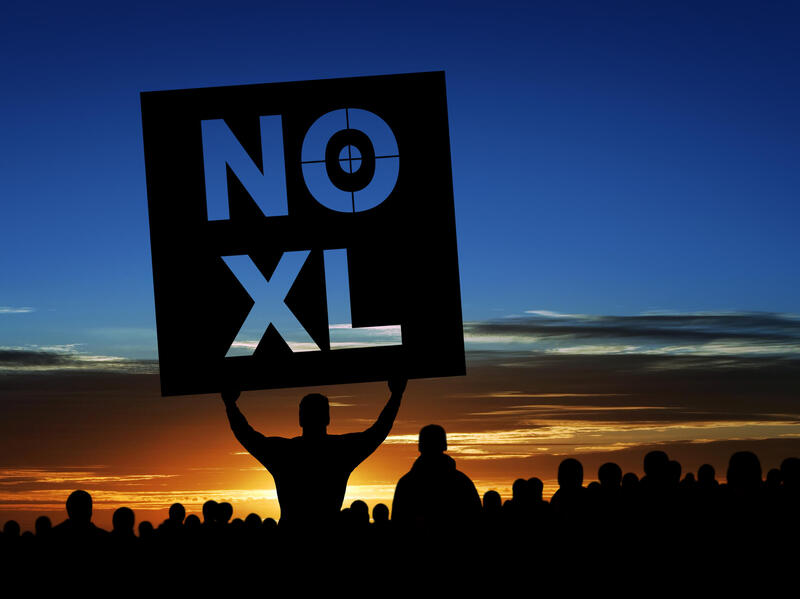 The silhouette of a person holding a sign that says \"NO XL\"
