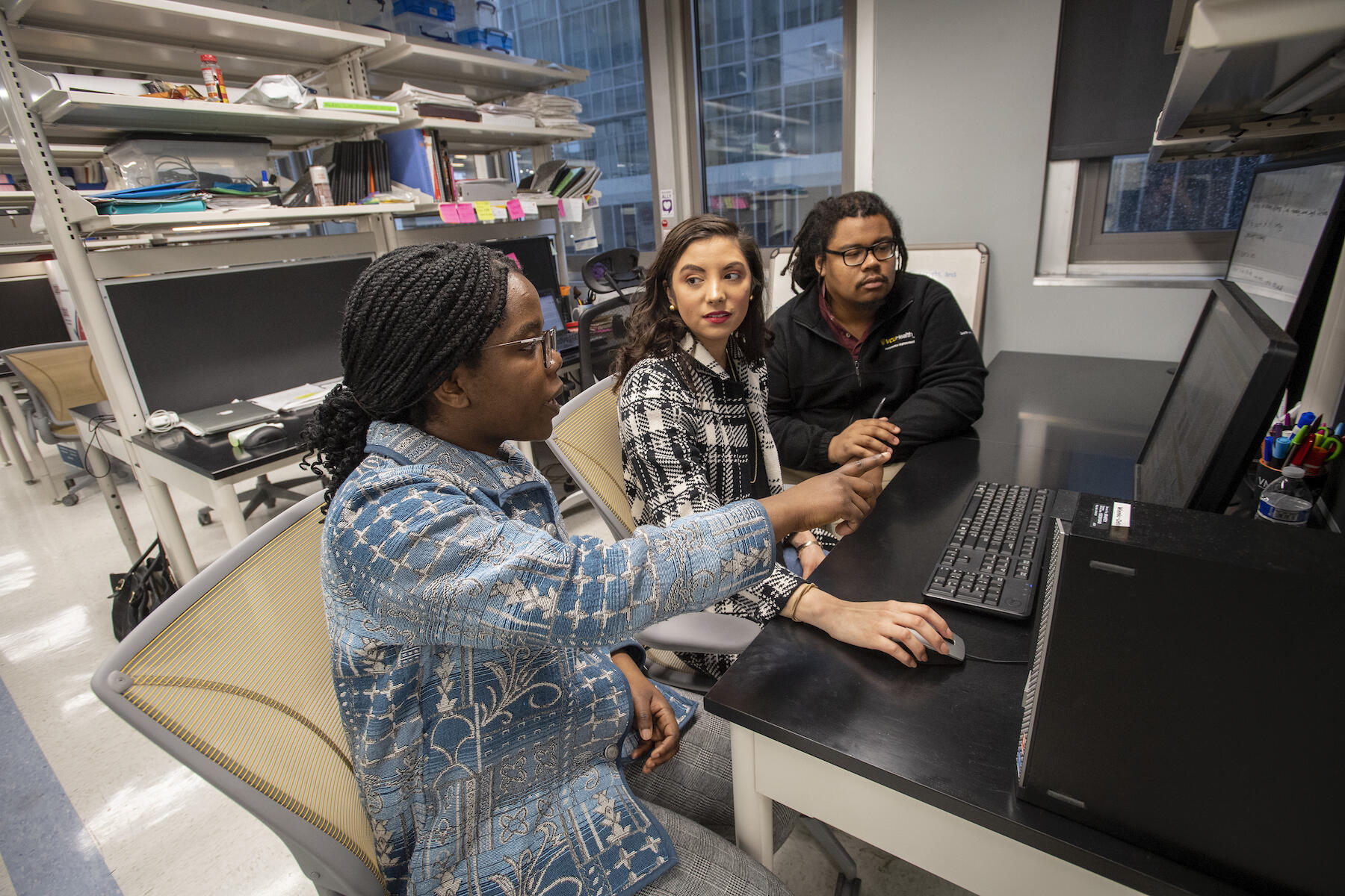 Three people seated at a table in a laboratory.