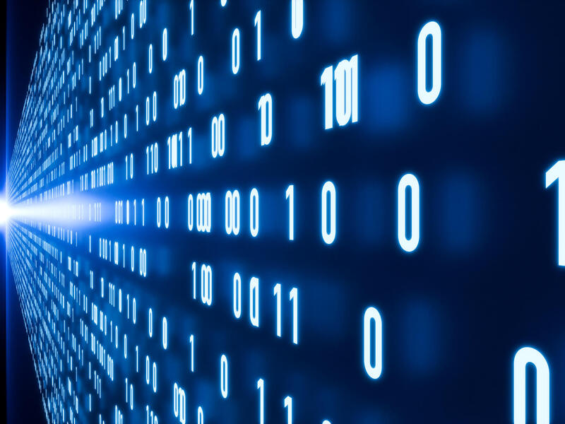 An image of binary code running against two walls that have a beam of light shining between them. 