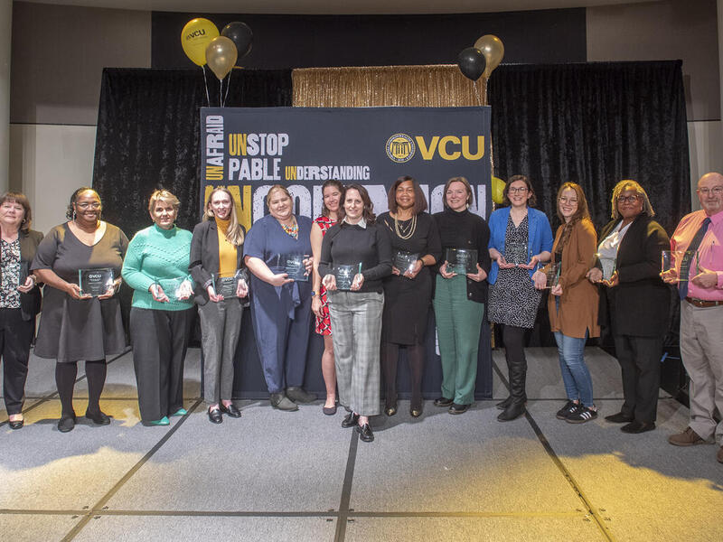 A group photo of 13 people standing on a stage 