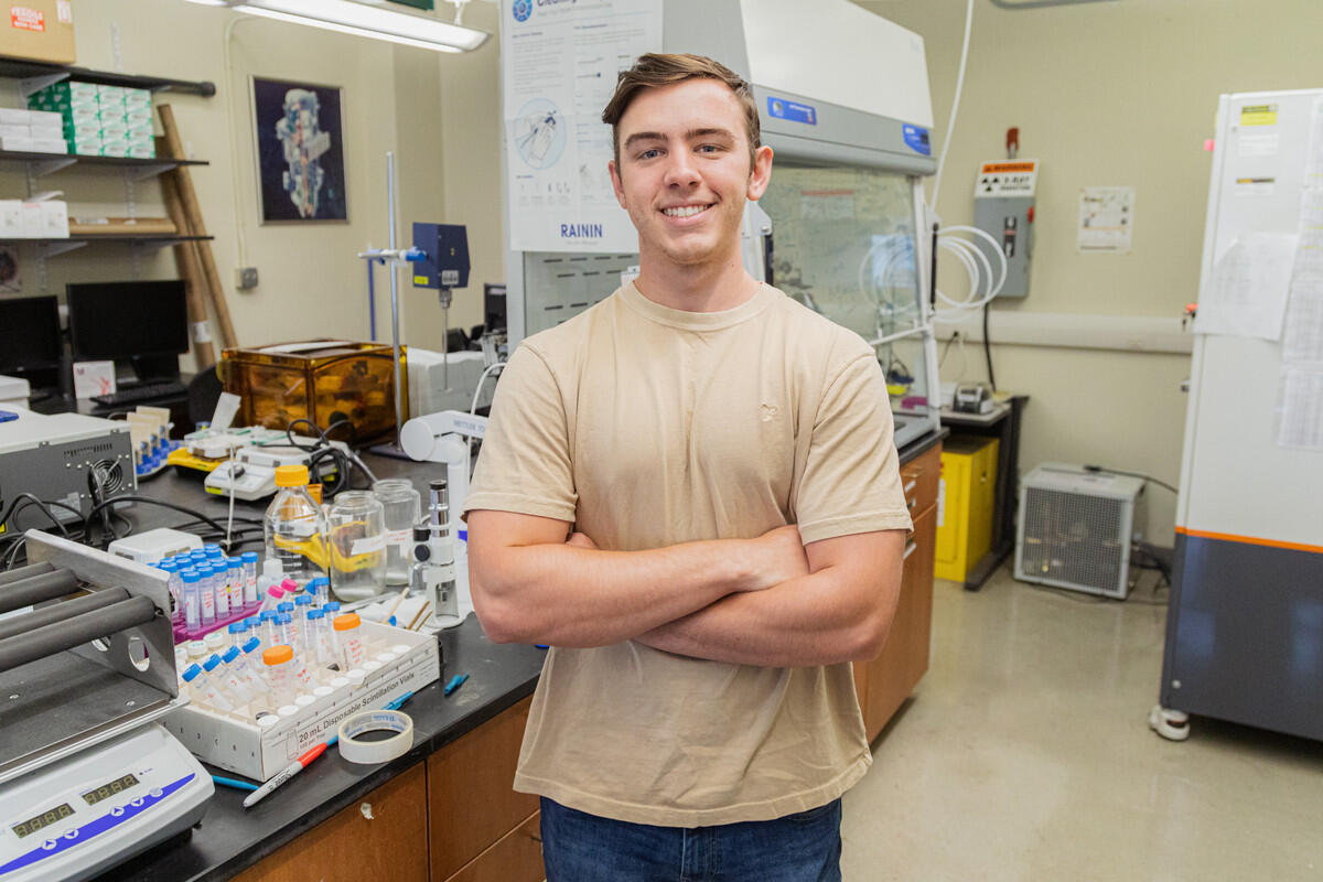 A man standing in the middle of a science lab with his arms crossed over his chest. 