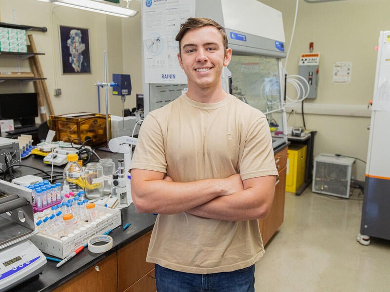 A man standing in the middle of a science lab with his arms crossed over his chest. 