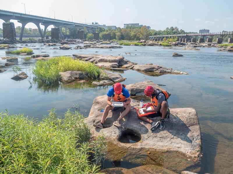 VCU students take samples from water pools collecting on rocks on the James River.
