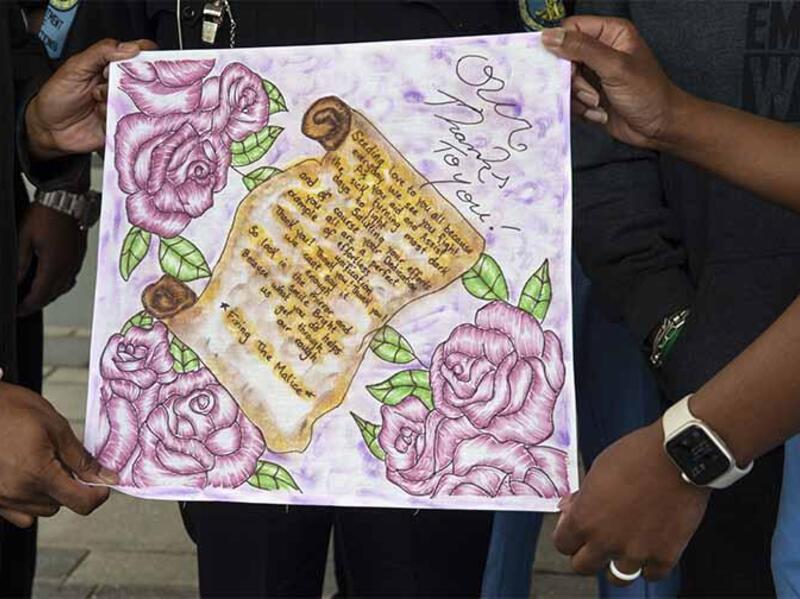 Two pairs of hands holding a thank you letter with roses drawn on it