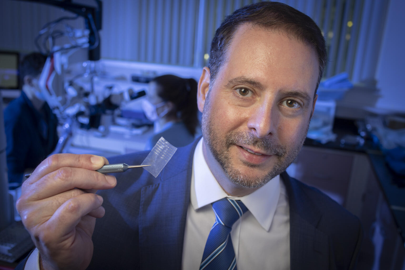 A photo of a man holding up a piece of tape with a sharp object