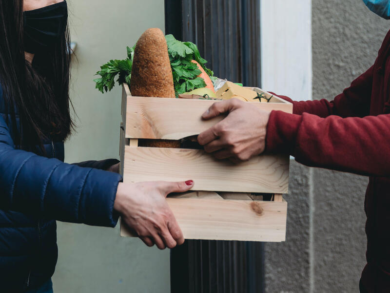 a person hands a box of produce to another person