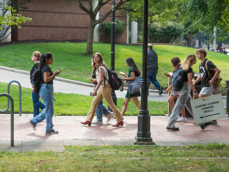 A photo of people walking across the sidewalk. 