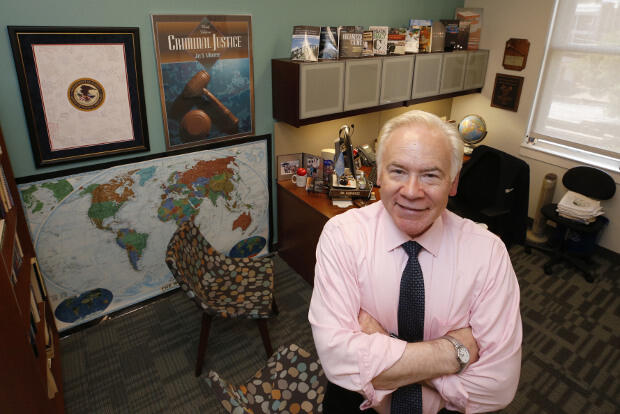 A man stands in front of a desk in an office.