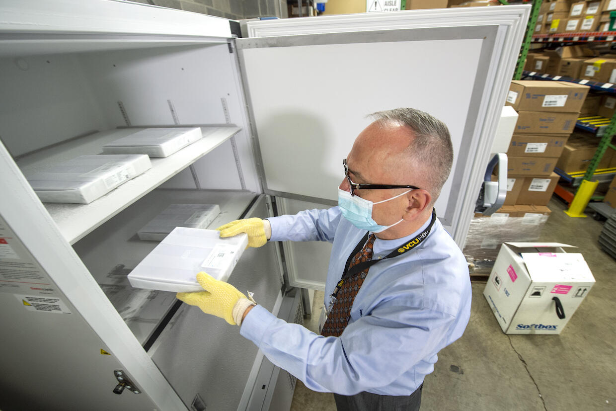 Rodney Stiltner placing a tray of COVID-19 vaccine vials into an ultra-cold freezer.