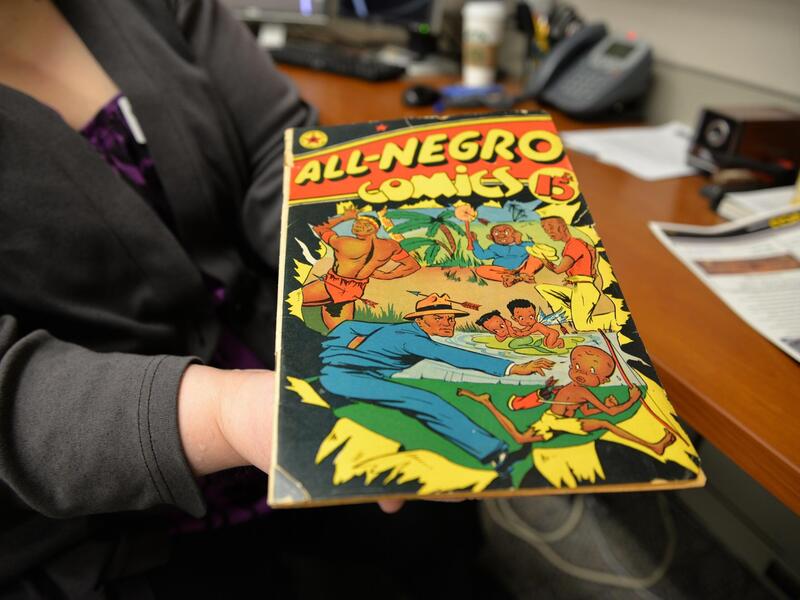 A photo ot a person holding out a comic book to show it. The cover says \"ALL-NEGRO cominics\" and has an image of a man chasing after a child.