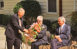 VCU President Dr. Eugene P. Trani presents a bouquet to Judith Fox, wife of former VCU president and Dr. Trani’s predecessor Edmund F. Ackell, who looks on during the dedication ceremony of the Ackell Residence Center.