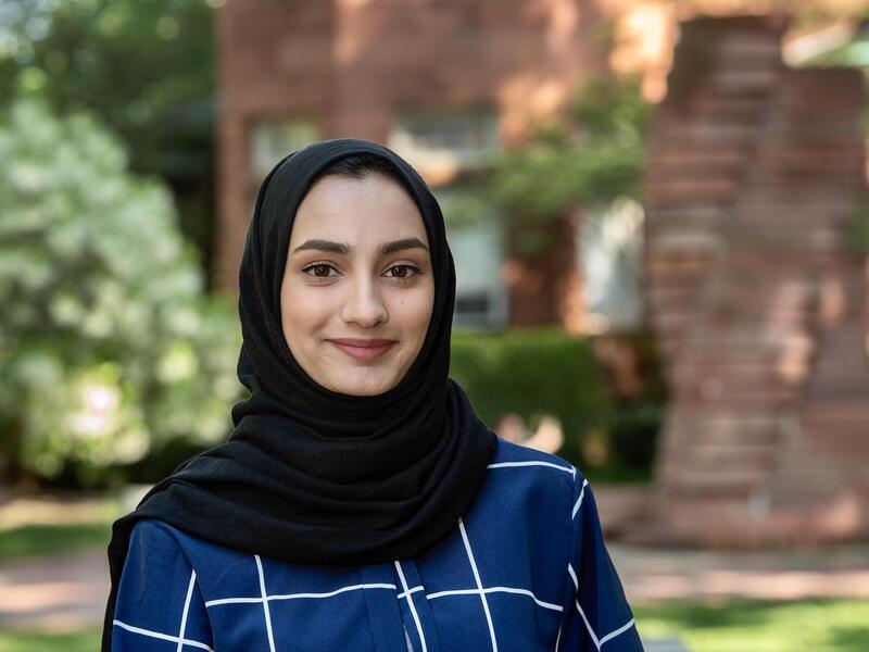 Samia Saleem wearing a black hijab and a dark blue blouse with white lines forming squares. 