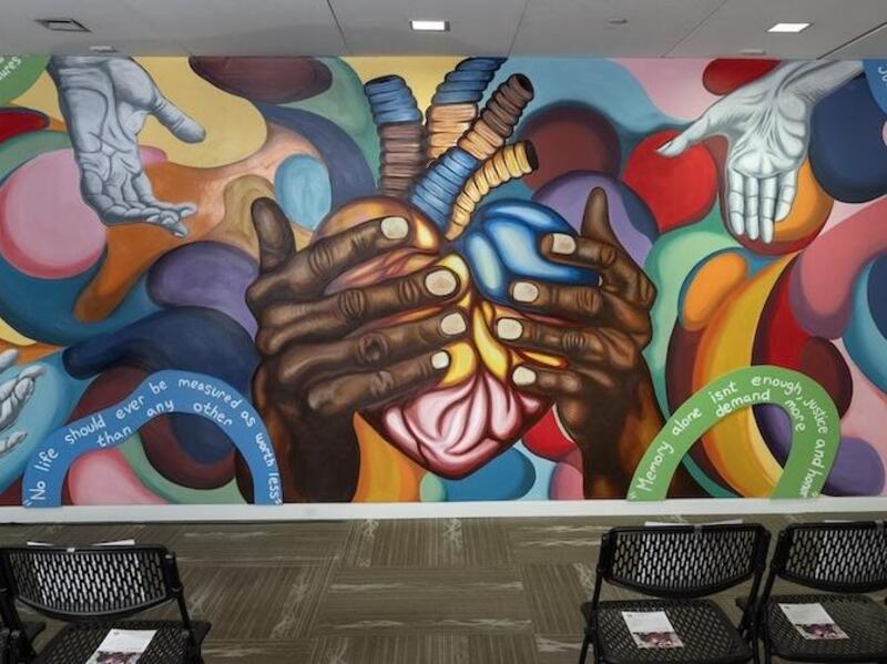 A colorful mural shows a pair of hands holding a multicolored mural.