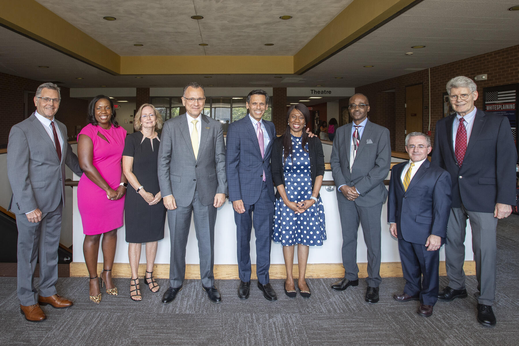 A photo of nine people standing next to each other. 