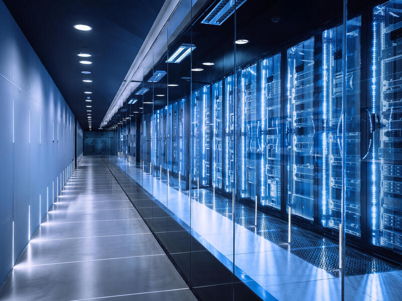 An image of a long hallway with data servers behind glass. 