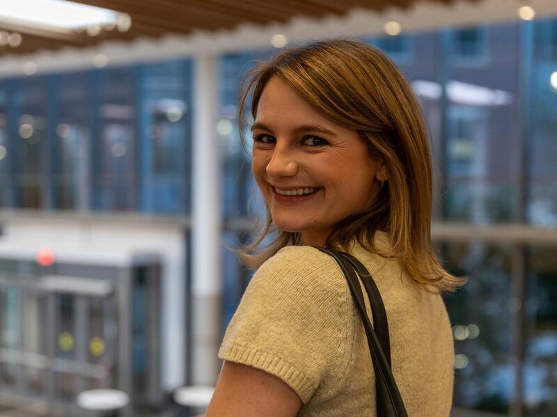 A photo of a woman smiling while looking back over her shoulder. 