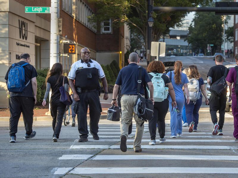 A smiling VCU Police officer monitors pedestrians in the crosswalk as they cross the street.
