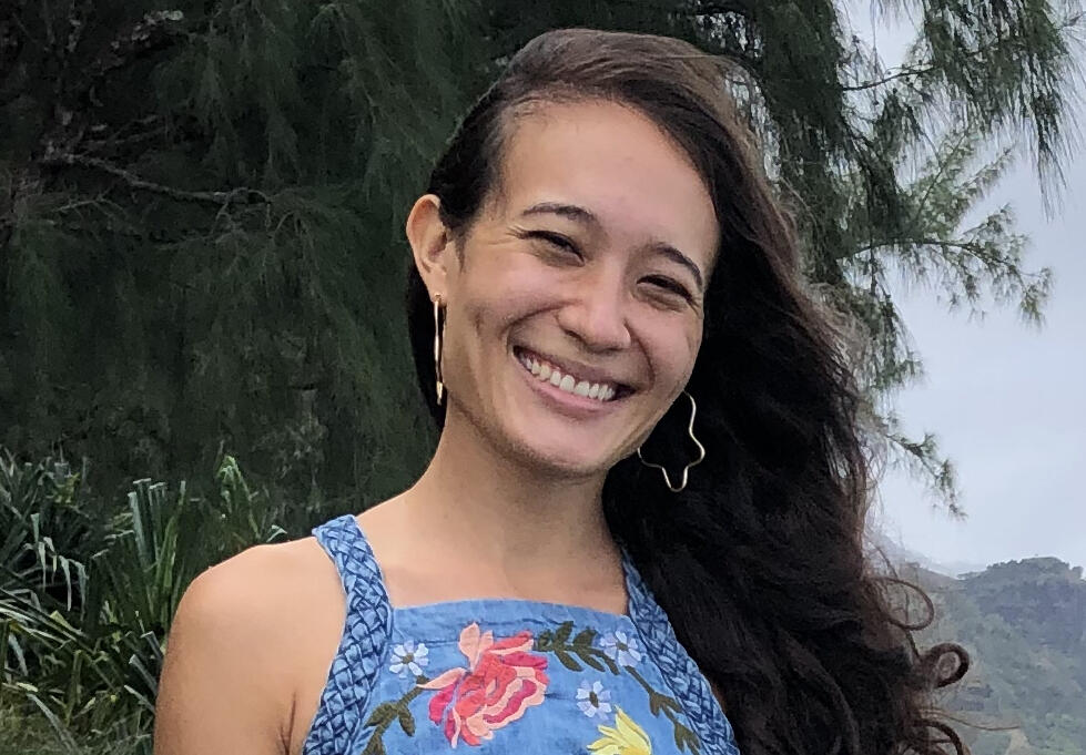 A portait of a woman wearing a blue dress with a floral pattern from the chest up