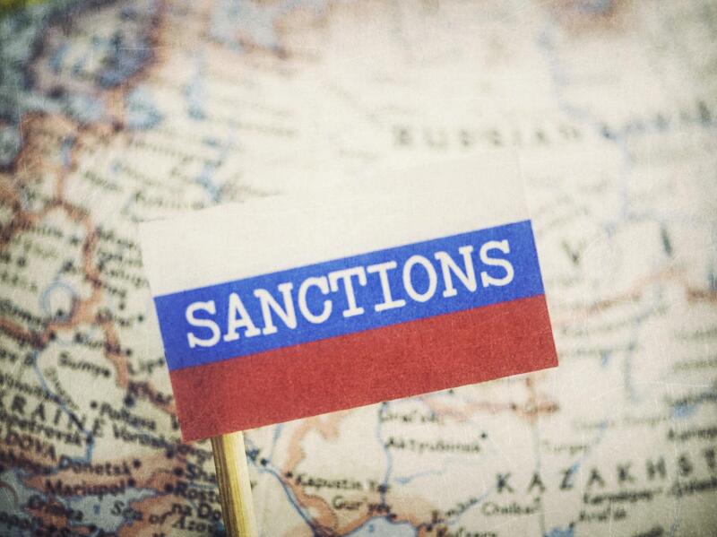 A Russian Flag that says \"Sanctions\" on it over a globe showing the country of Russia
