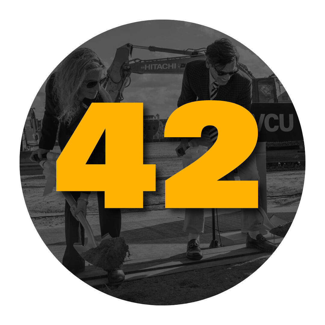 The number 42 overlaying a photo of officials shoveling dirt at a groundbreaking ceremony.
