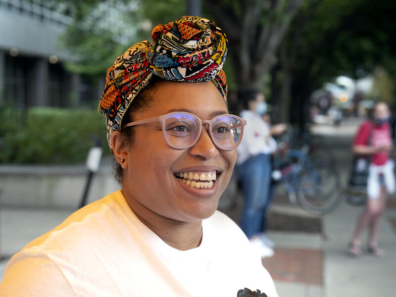 A woman wearing a headscarf and glasses looking to the right 