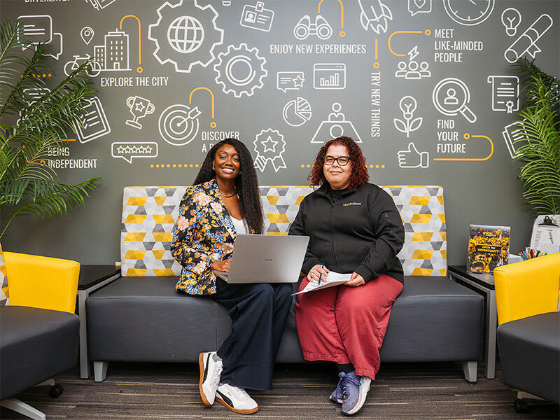 A photo of two women sitting on a couch. 