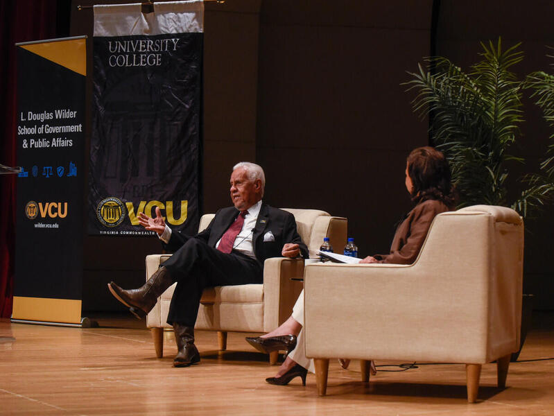 Two people sitting in arm chairs on a stage 