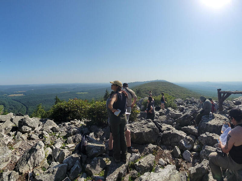 People are spread across a scenic rocky mountain lookout.