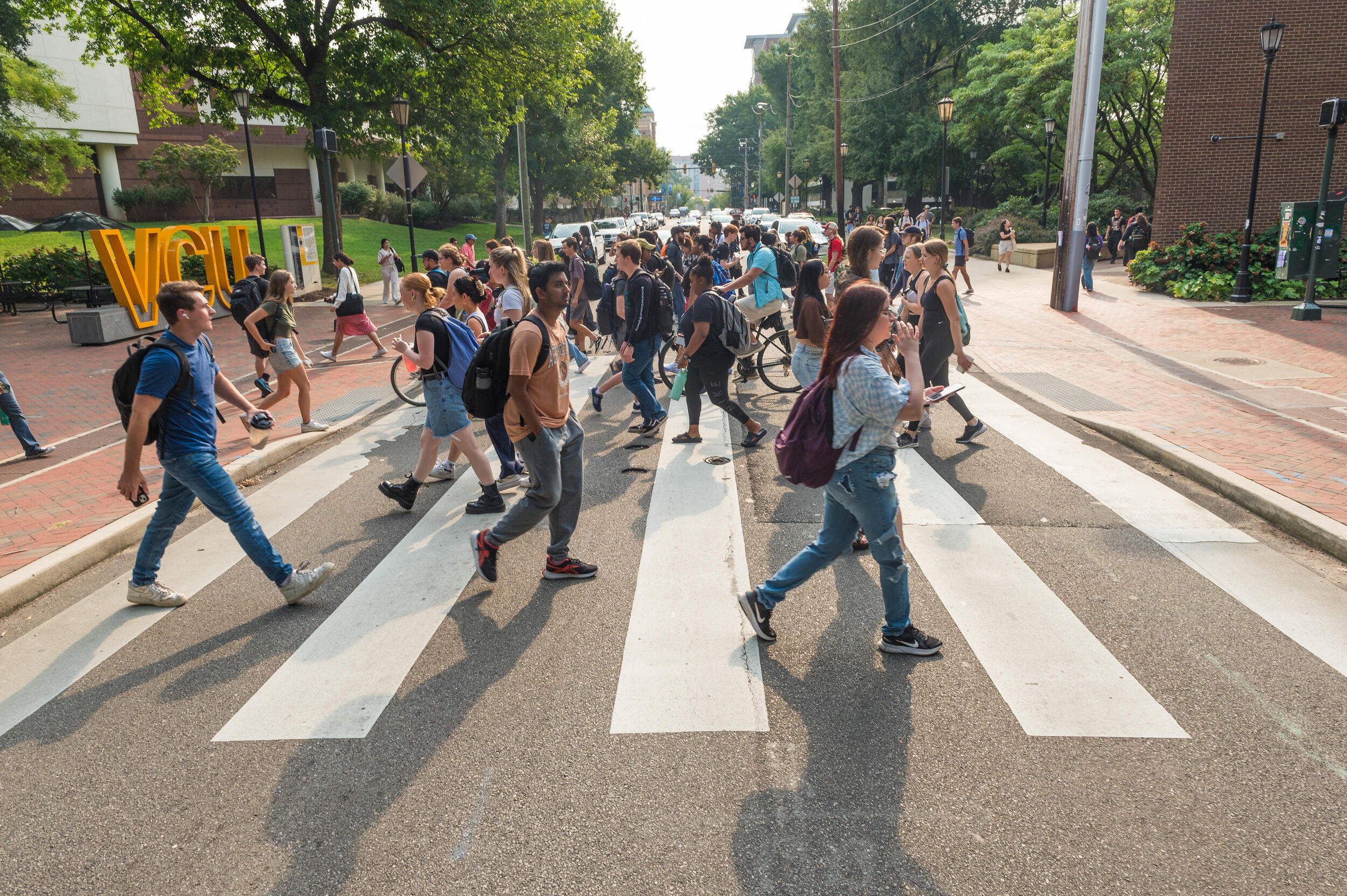 A crowd of people walking across a cross walk 