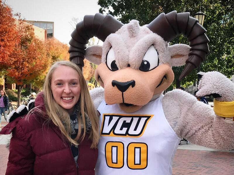 A Rodney the Ram mascot standing next to a woman.