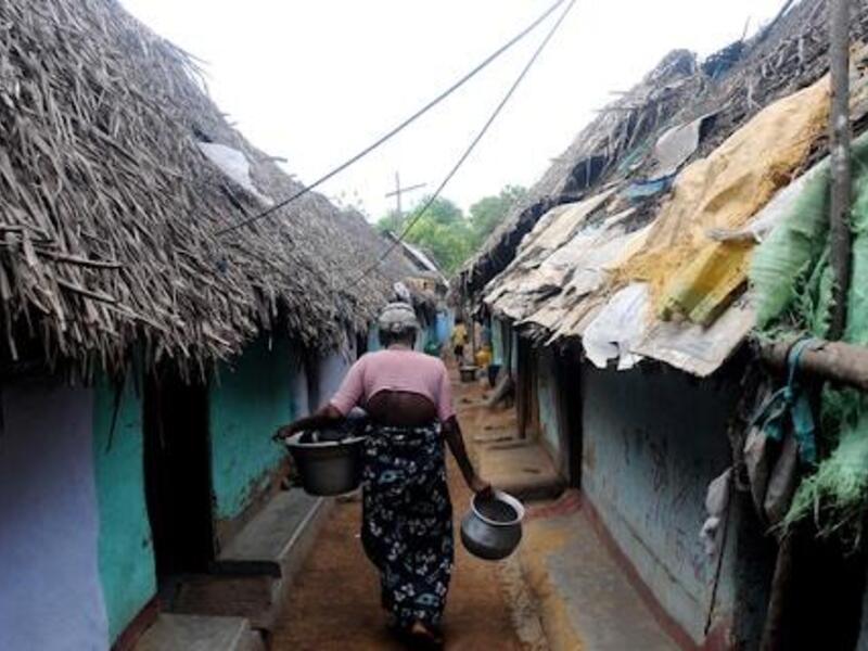 woman walking between huts in a refugee camp
