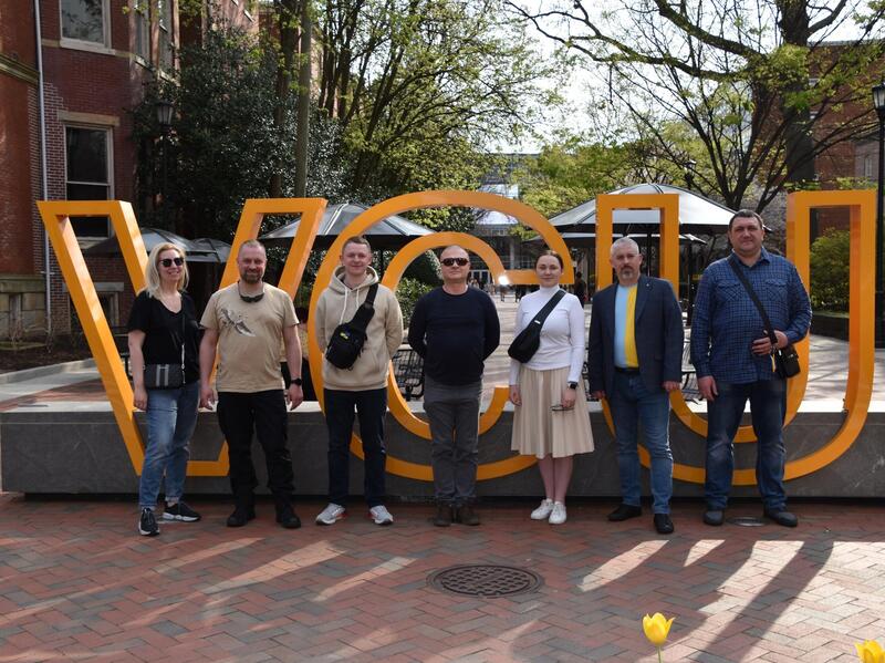 Six people in front of giant yellow letters that spell \"VCU\"