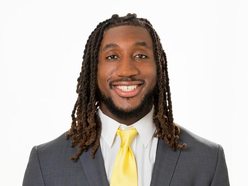 A man wearing a gray suit jacket, white button up shirt, and a yellow tie. 