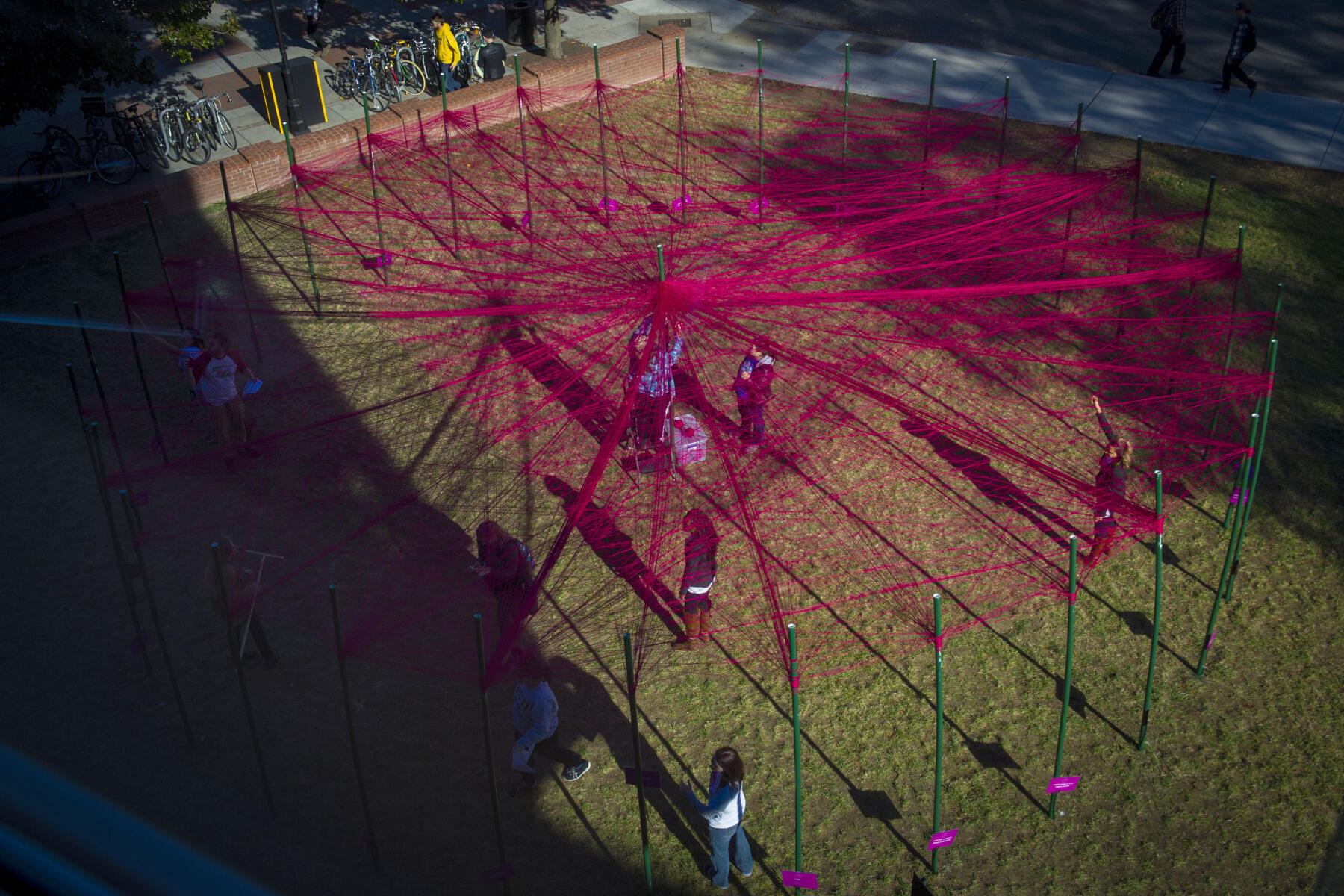 The UNITY Project, installed outside of Cabell Library, features a circular arrangement of 32 poles. Participants are asked to use string to wrap around each pole with which they identify.
