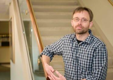 Oleg Korenok resting his arm on the railing of a staircase