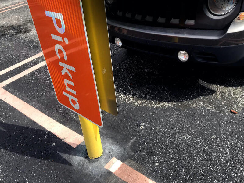 A car parked in front of a sign that says \"pickup.\"
