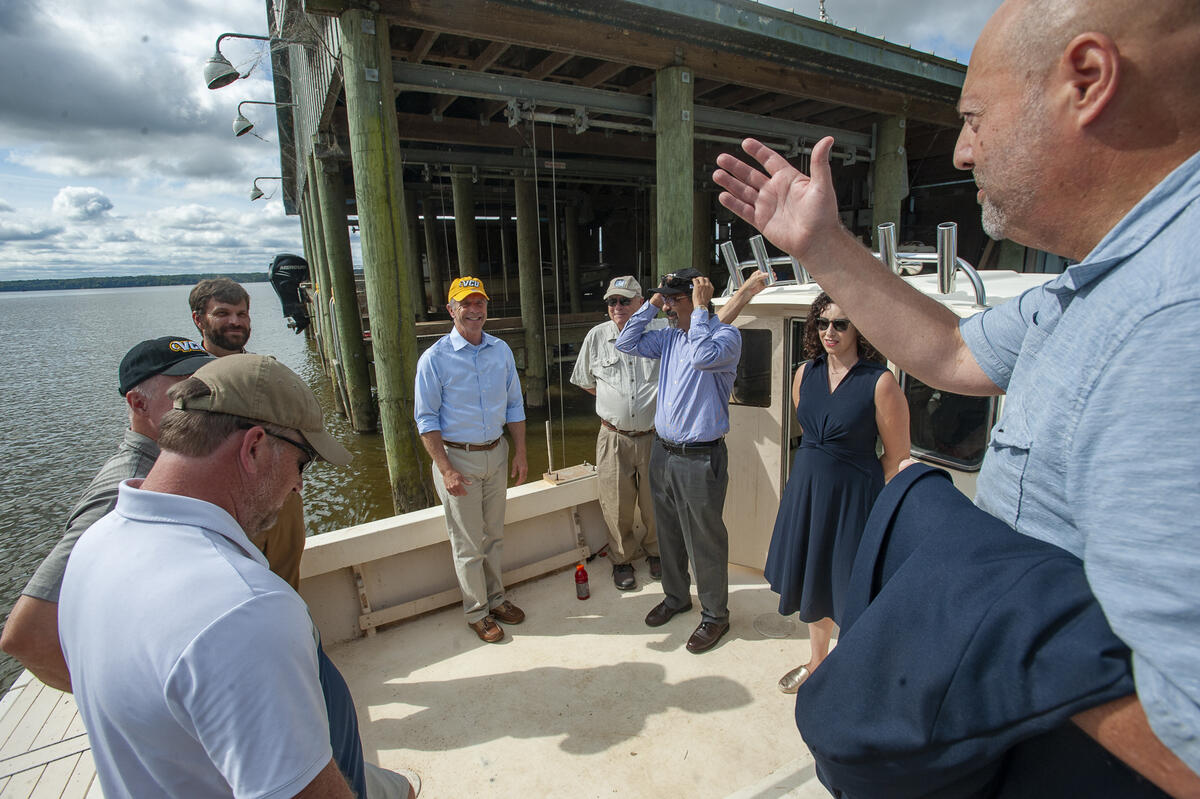Eight people standing in a semi-circle on a doc 
