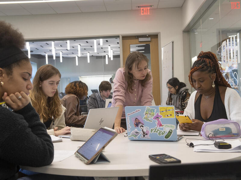 A photo of a womans tanding at a table full of students. 