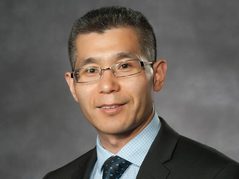 A photo of a man wearing a suit and tie, as well as glasses. 