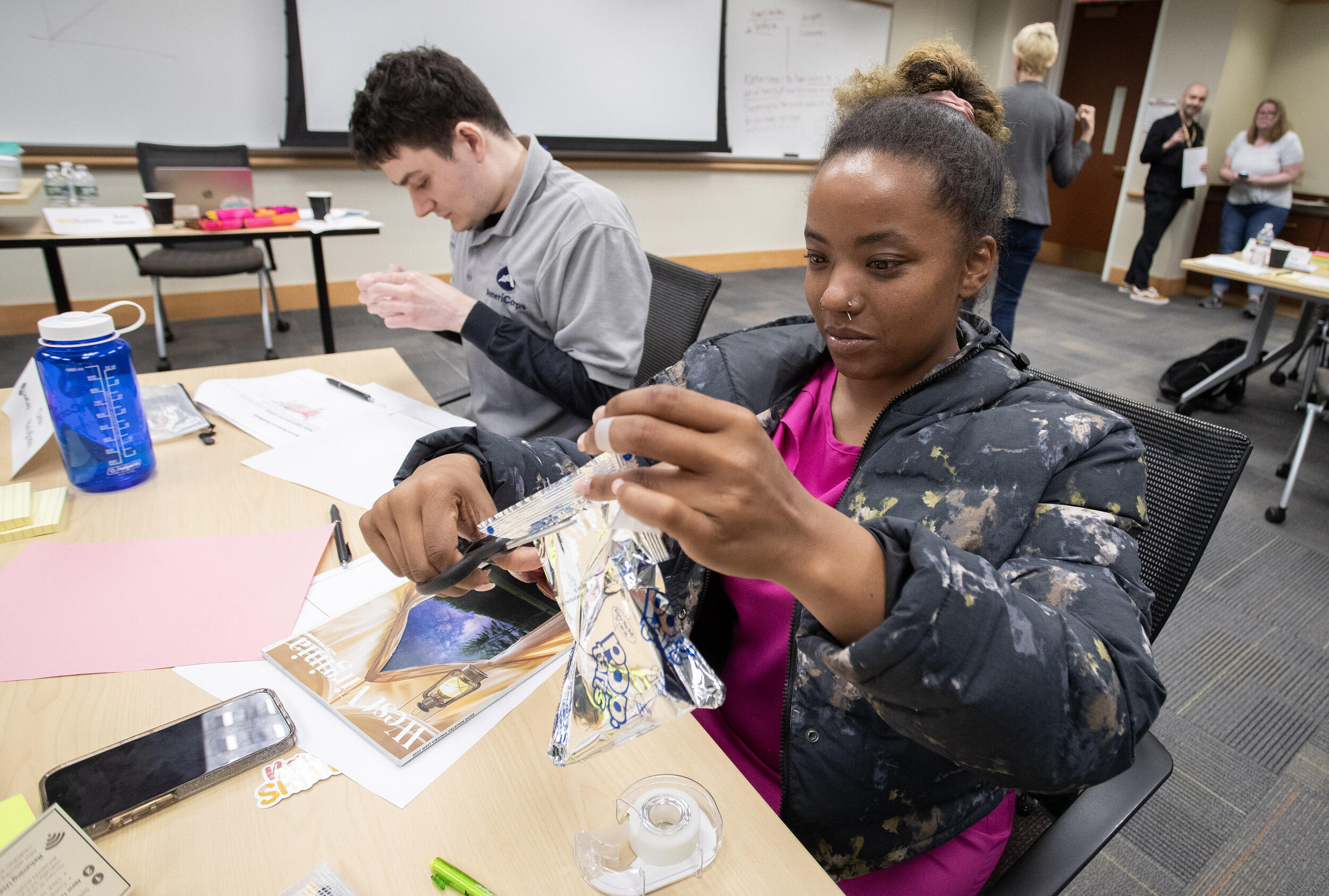 A photo of two students sitting at a table doing crafting activities. 