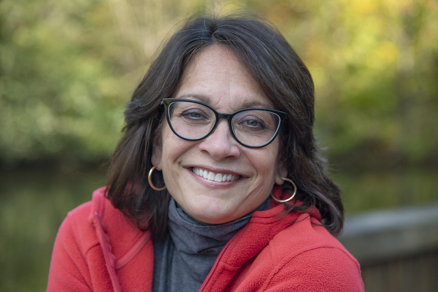 A photo of a woman wearing glasses and smiling from the shoulders up