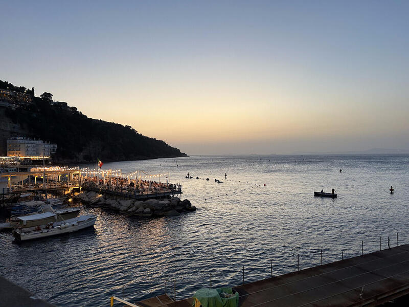 A photo of a coastline at dusk with a lit up pier