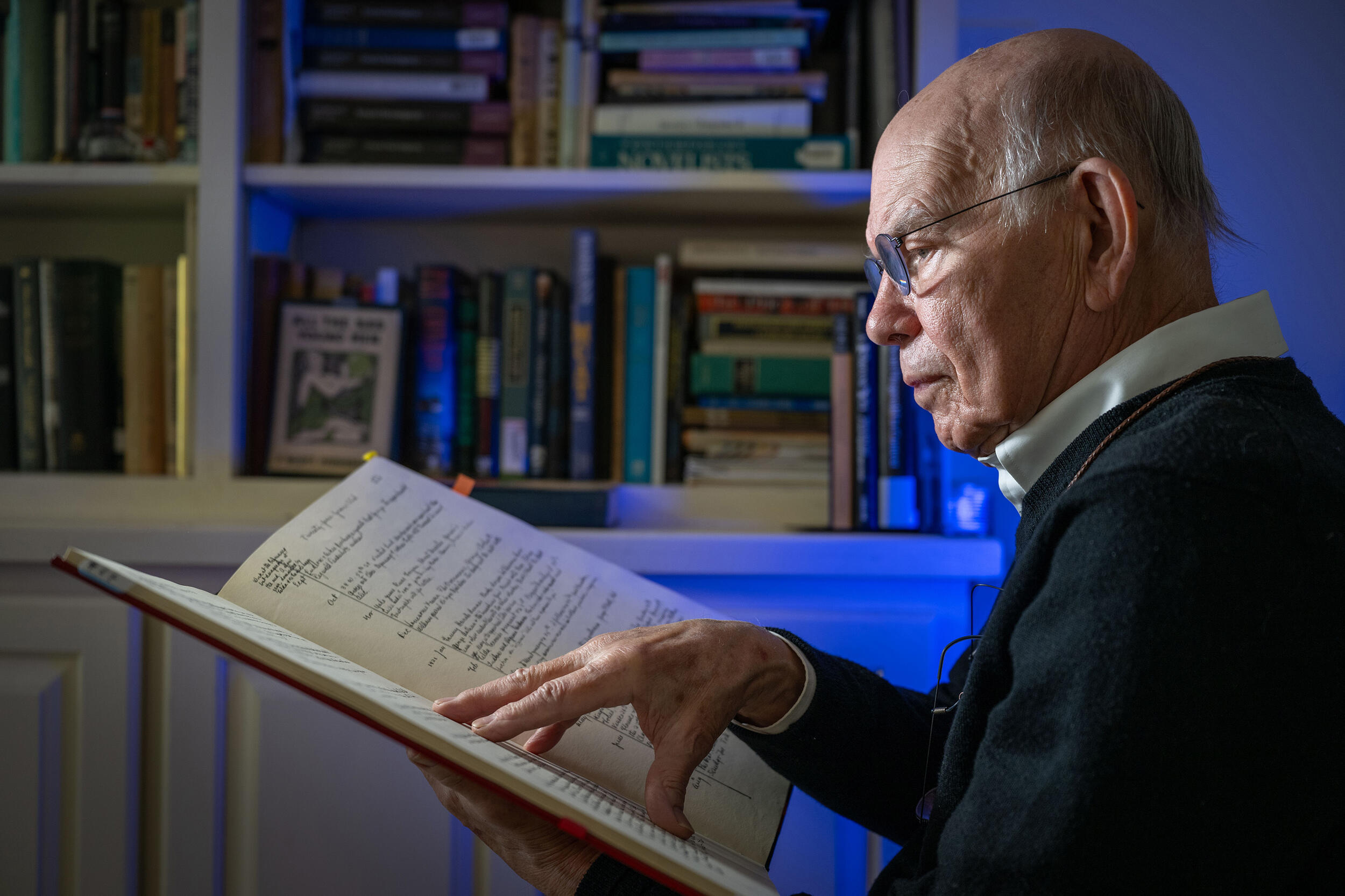 A photo of a man reading a large book. 
